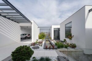 Moderní zahrada s koupacím jezírkem, betonovými terasami a proskleným obytným prostorem.