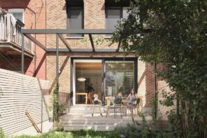 Dřevěná terasa s pergolou navazující na zadní část domu a orientovaná do soukromé zahrady.