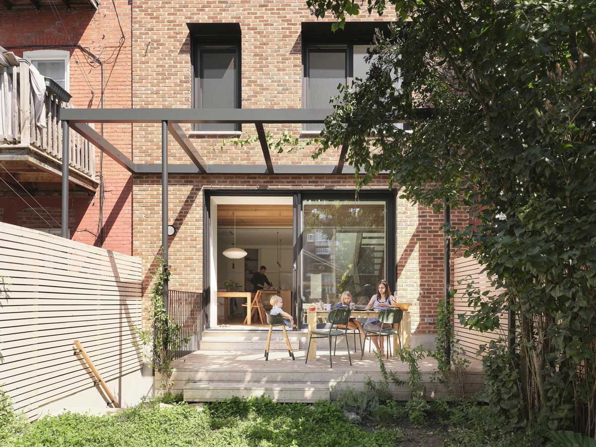 Dřevěná terasa s pergolou navazující na zadní část domu a orientovaná do soukromé zahrady.