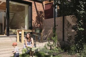 Rodina tráví čas na malé zahradě orientované na jihozápad se vzrostlým šeříkem.