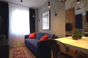 Jídelní kout v malé garsonce se zrcadlem, které opticky zvětšuje prostor a odráží denní světlo