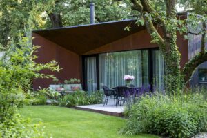 Zahrada s terasou a vzrostlou zelení, která poskytuje stín a příjemné mikroklima