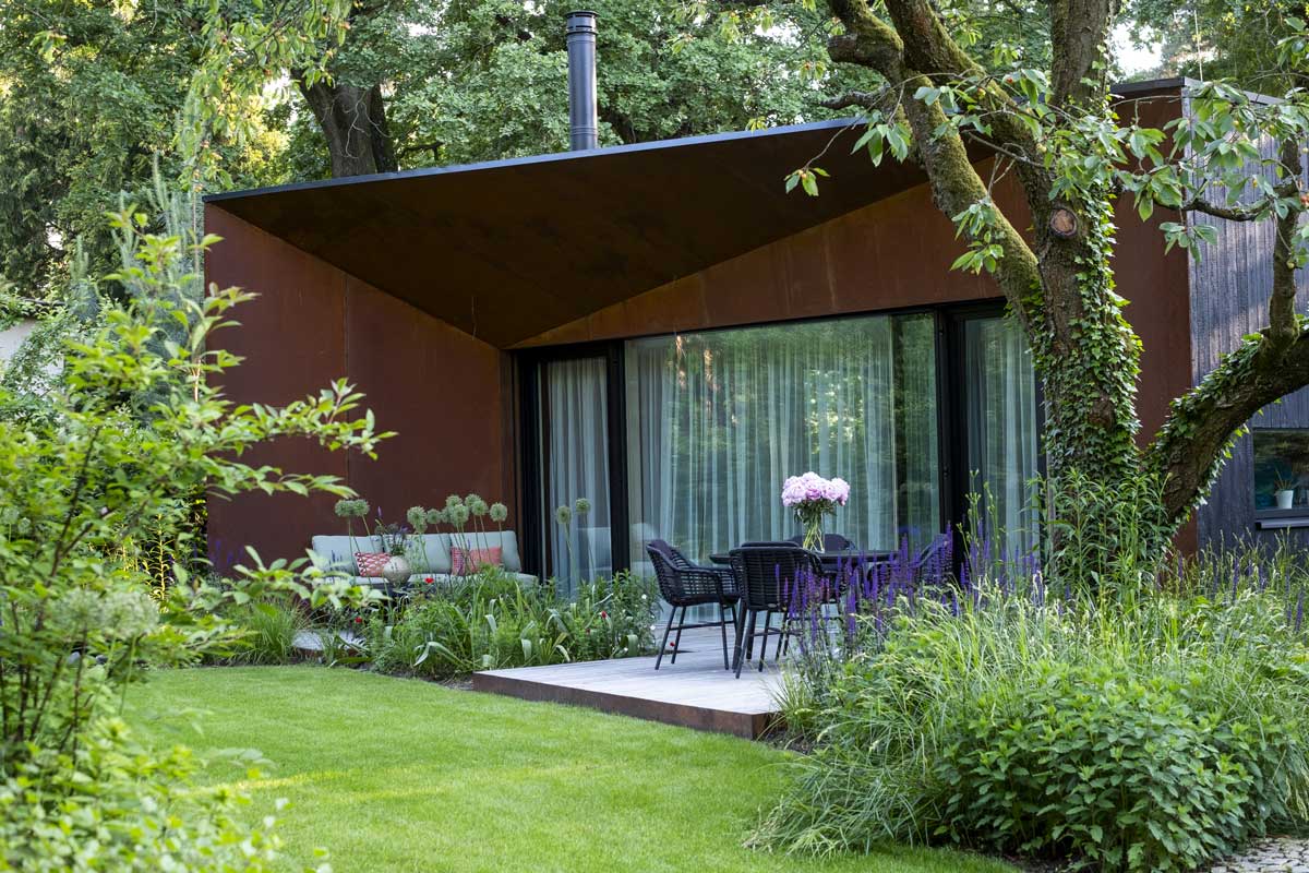 Zahrada s terasou a vzrostlou zelení, která poskytuje stín a příjemné mikroklima