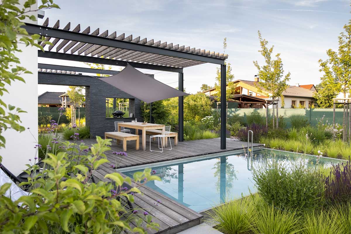Moderní zahrada s pergolou a venkovním posezením, která umožňuje trávit čas venku po celý rok