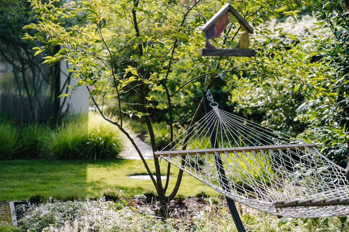 Zahrada s houpací sítí a vzrostlou zelení jako místo pro relaxaci a zpomalení