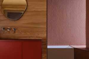 Koupelna s červenou skříňkou, dřevem a vanou v útulném, tlumeném prostoru