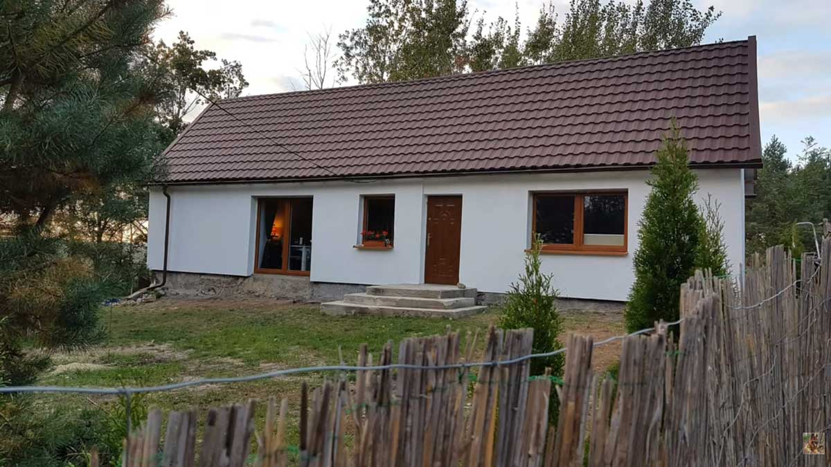 Zrekonstruovaný dům se světlou fasádou a sedlovou střechou obklopený zelení