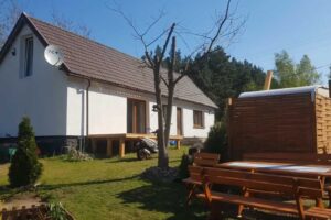 Dům s dřevěnou terasou a zahradou uprostřed přírody