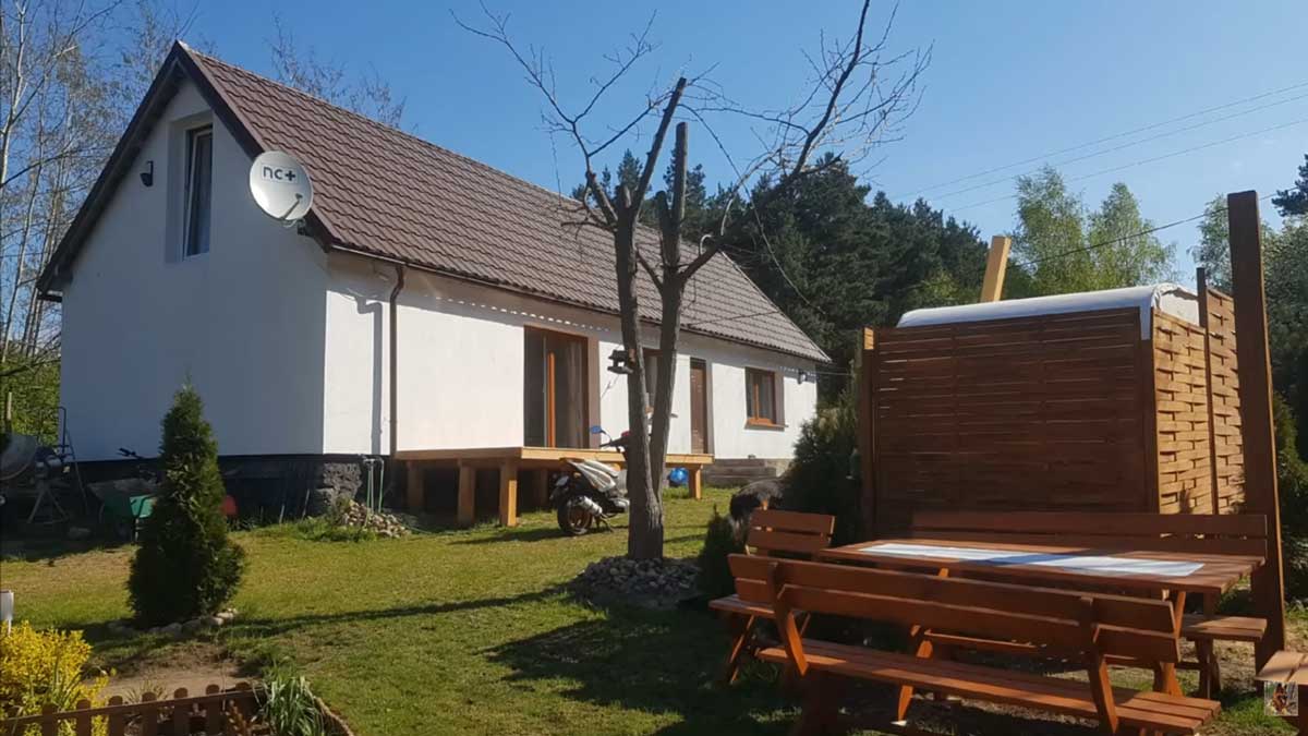 Dům s dřevěnou terasou a zahradou uprostřed přírody