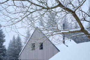 Chalupa zasazená do hlubokého sněhu ve strmém svahu
