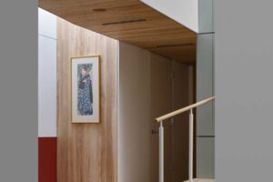 Interiér chodby s dřevěnými prvky, schodištěm a jemnými barevnými akcenty.