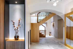 Vstupní část bytu s oblými klenbami podsvícenou zrcadlovou stěnou a nábytkem vyrobeným na míru.