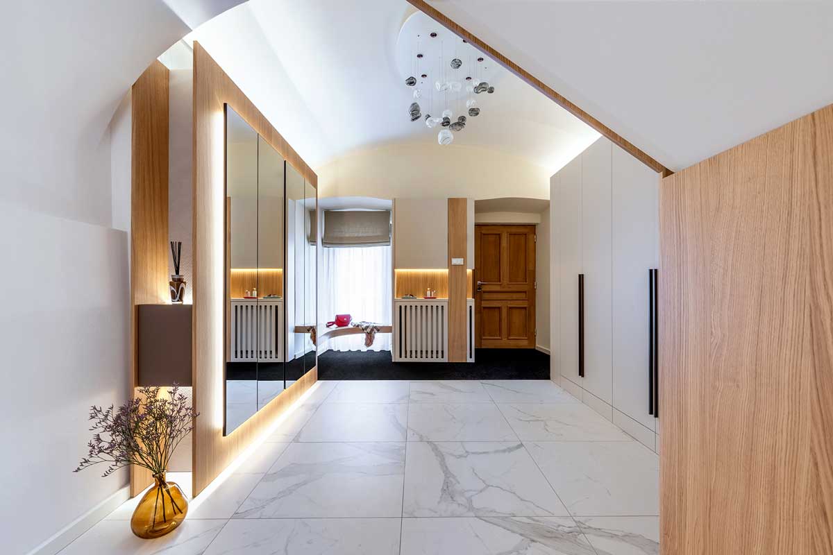 Prostor vstupu s vestavěnou šatní skříní z přírodní dýhy a výraznými černými madly.