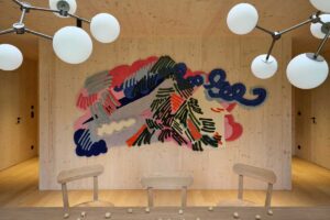 Pohled na chalupu s velkoformátovým oknem zasazenou do lesního prostředí