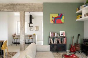 Pohled z obývací části do otevřené kuchyně kde se setkává historická dlažba betonová konstrukce a moderní minimalistická kuchyň.