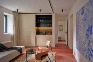 Otevřený obytný prostor s velkým oknem a výhledem do lesa