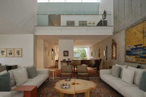 Prostorný obývací pokoj s vysokým stropem, galerií a kombinací betonu a dřeva Titulek: Otevřený prostor propojuje jednotlivé funkce domu a zároveň zachovává pocit