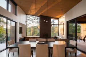 Otevřený obývací prostor s jídelnou, vysokým stropem a prosklenými stěnami.