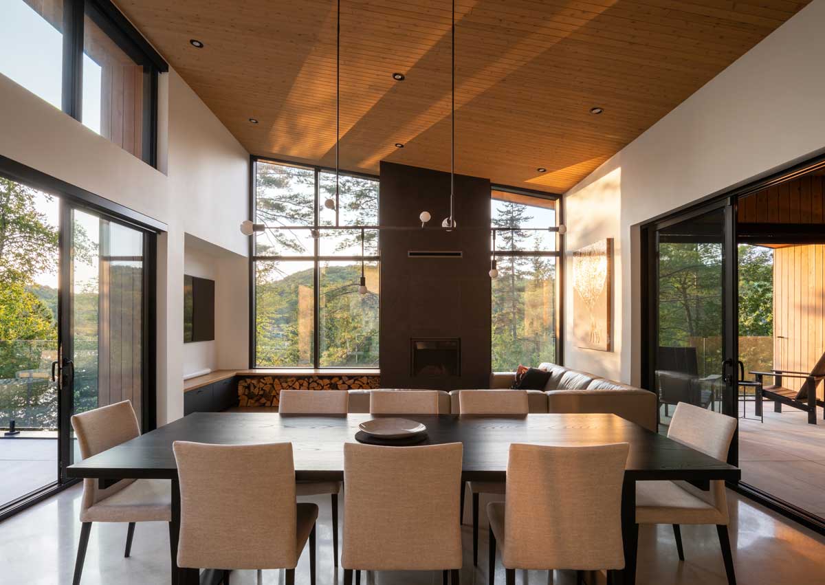 Otevřený obývací prostor s jídelnou, vysokým stropem a prosklenými stěnami.