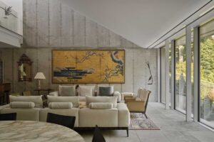 Moderní obývací prostor s velkým obrazem na betonové stěně a výhledem do přírody