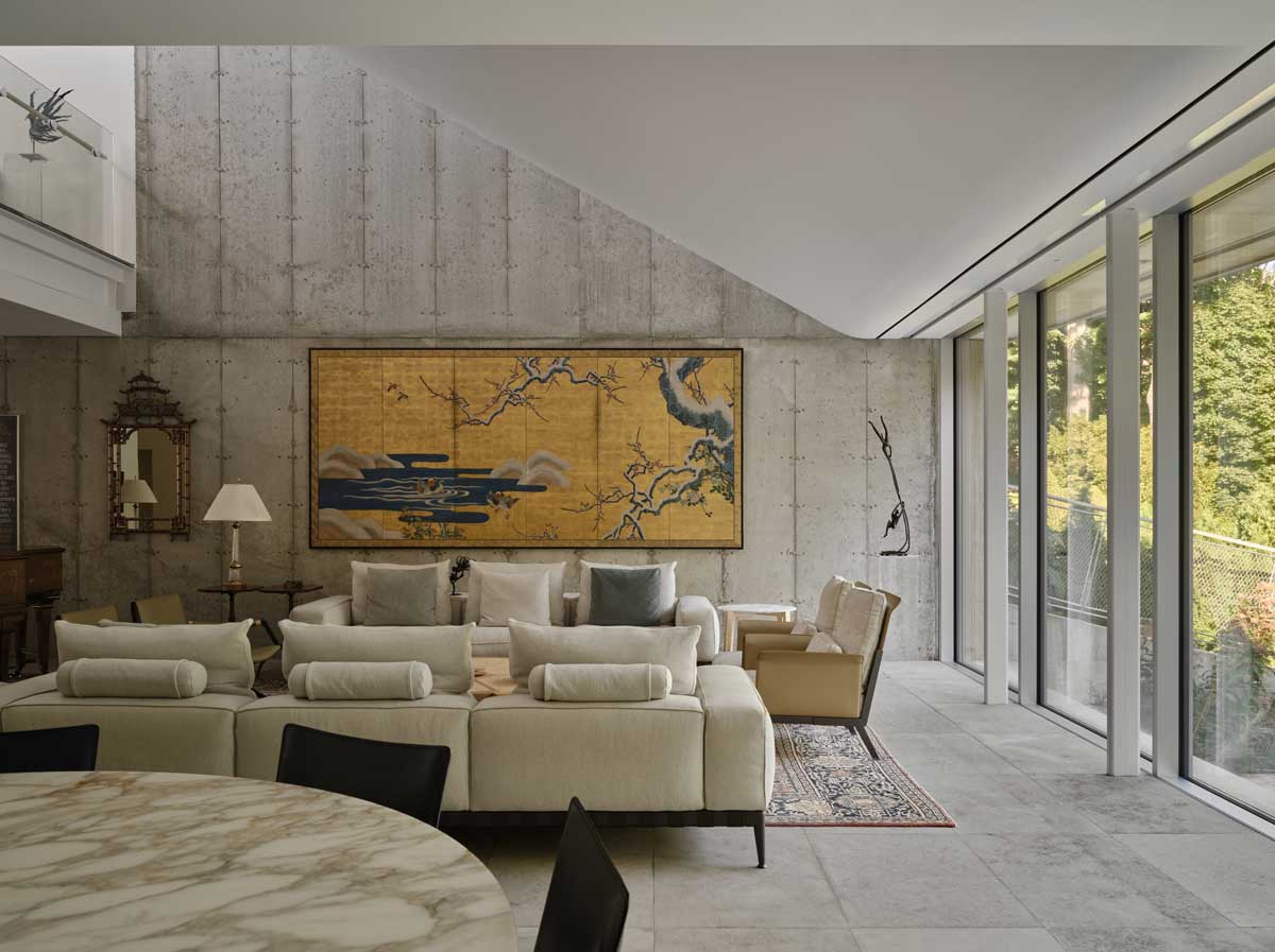 Moderní obývací prostor s velkým obrazem na betonové stěně a výhledem do přírody