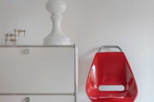 Detail retro židle ze staré tramvaje vedle kovové komody v interiéru bytu architektů