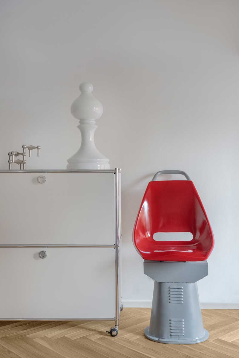 Detail retro židle ze staré tramvaje vedle kovové komody v interiéru bytu architektů