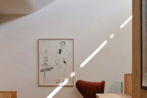 Útulný kout s červeným křeslem, dřevěným nábytkem a jemným světlem dopadajícím na stěnu