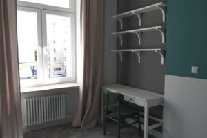 Světlý pokoj s pracovním stolem a policemi, který může sloužit jako pracovna nebo budoucí dětský pokoj.