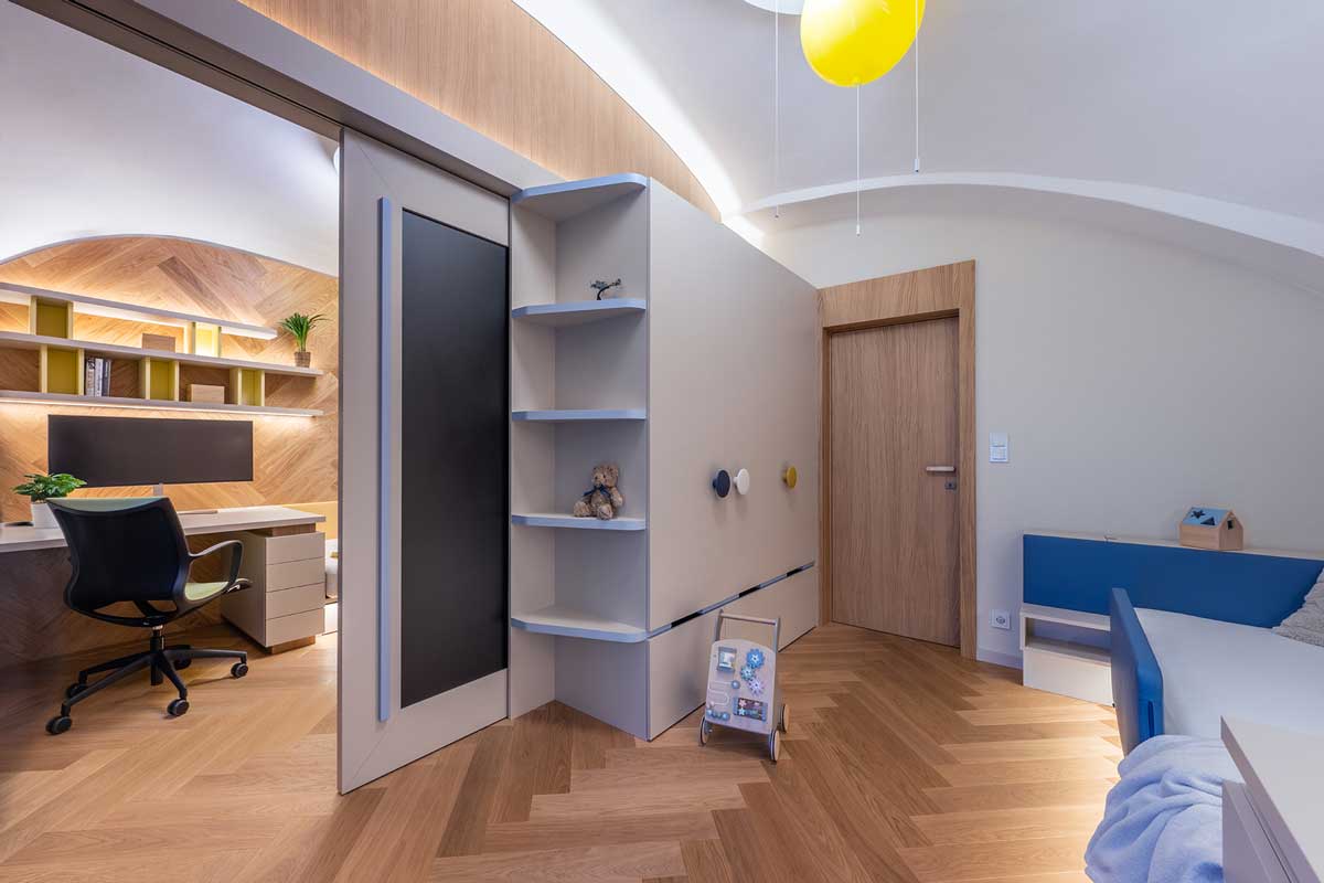 Dětský pokoj s vestavěným nábytkem na míru a pracovním koutem propojený s dalším pokojem posuvnými dveřmi.