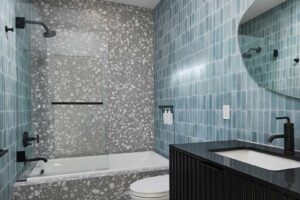 Moderní koupelna s modrými obklady a výraznou strukturou působí svěže a elegantně.