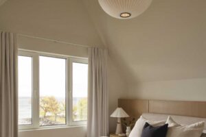 Druhá ložnice se světlým interiérem a výhledem na jezero působí vzdušně a klidně