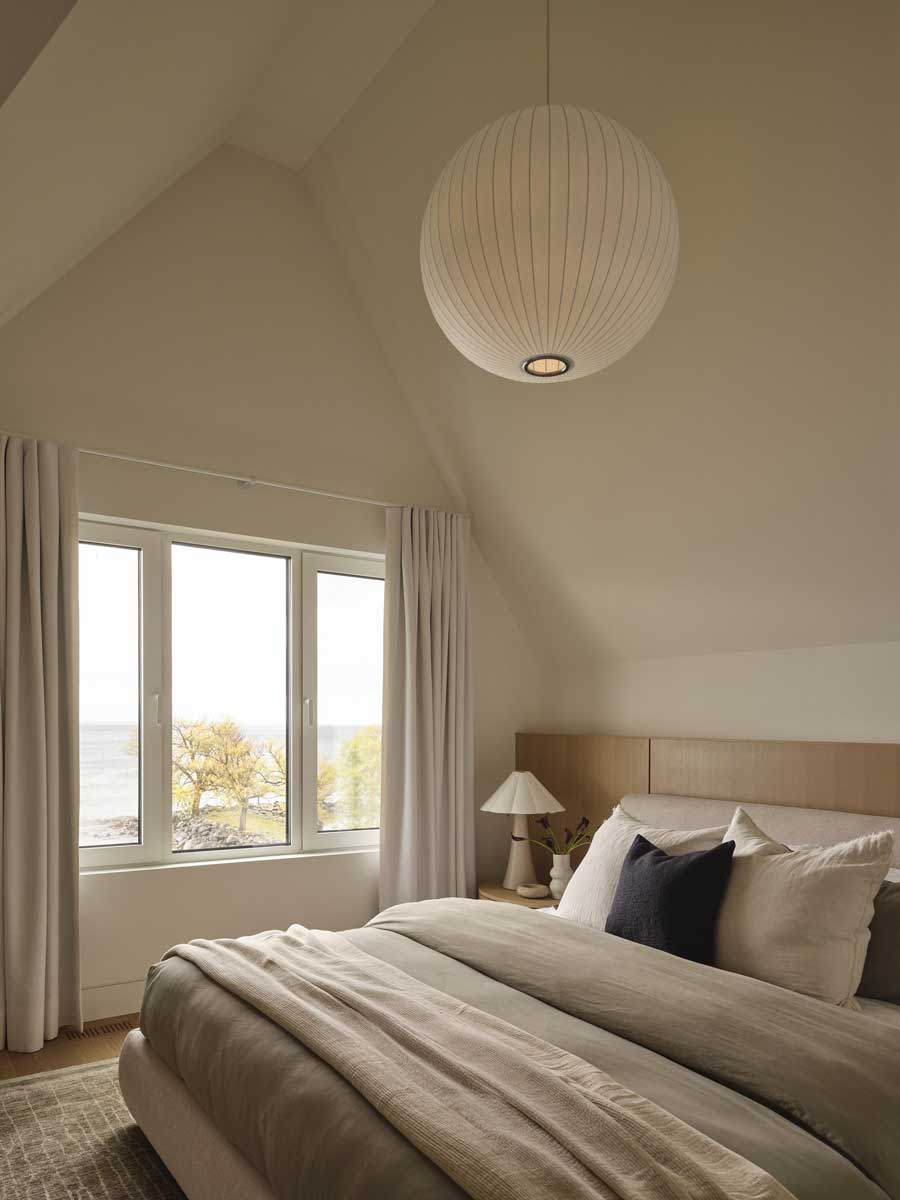 Druhá ložnice se světlým interiérem a výhledem na jezero působí vzdušně a klidně