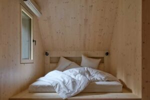 Útulná ložnice pod střechou s vestavěným lůžkem a dřevěným obkladem