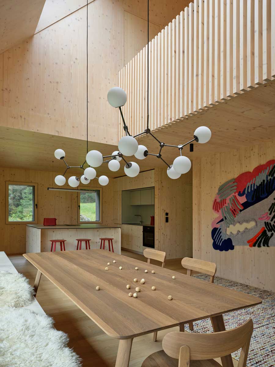 Propojená jídelna s kuchyní v otevřeném dřevěném interiéru