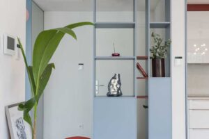 Vestavěná knihovna ve světle modrém odstínu odděluje vstupní prostor od denní zóny a zároveň nabízí místo pro knihy a dekorace.