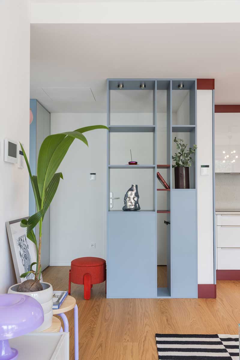 Vestavěná knihovna ve světle modrém odstínu odděluje vstupní prostor od denní zóny a zároveň nabízí místo pro knihy a dekorace.