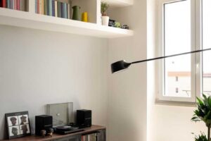 Nízká knihovna s vinylovými deskami gramofonem a dekoracemi umístěná pod vestavěnými policemi v obývací části.