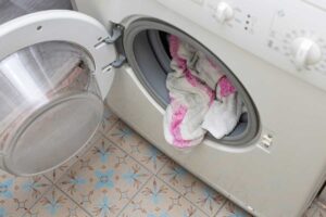 Prostor kolem pračky, kde se hromadí prach, vlákna z prádla a vlhkost při běžném provozu