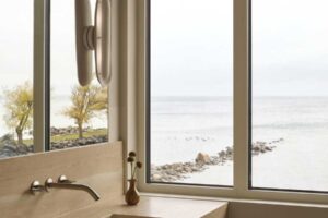 Koupelna s dřevěným dekorem a výhledem na jezero propojuje interiér s okolní krajinou