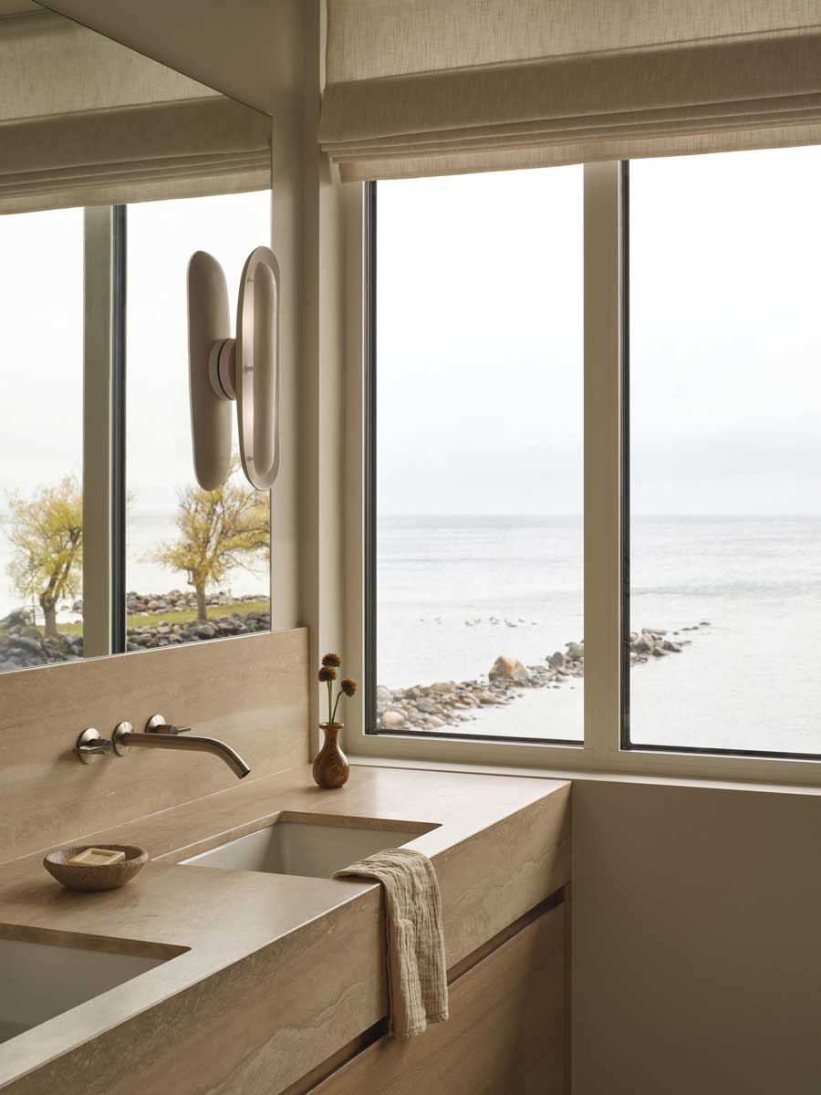 Koupelna s dřevěným dekorem a výhledem na jezero propojuje interiér s okolní krajinou