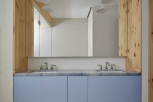 Koupelna s dřevěným obkladem, dvojitým umyvadlem a světle modrou skříňkou