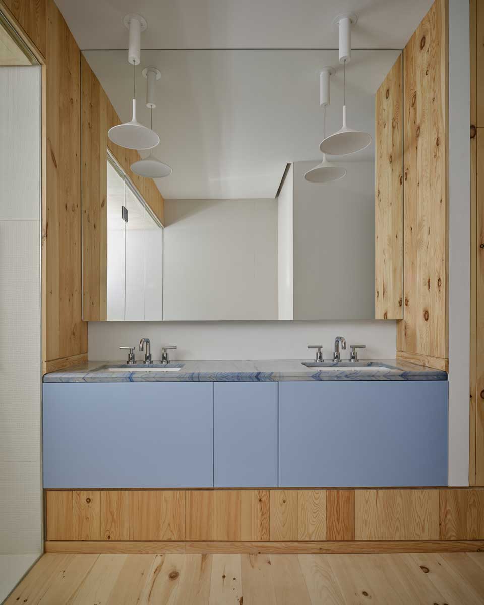 Koupelna s dřevěným obkladem, dvojitým umyvadlem a světle modrou skříňkou