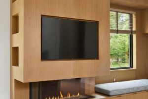 Vestavěná obývací stěna s krbem a televizí kombinuje dřevo s moderním řešením prostoru.