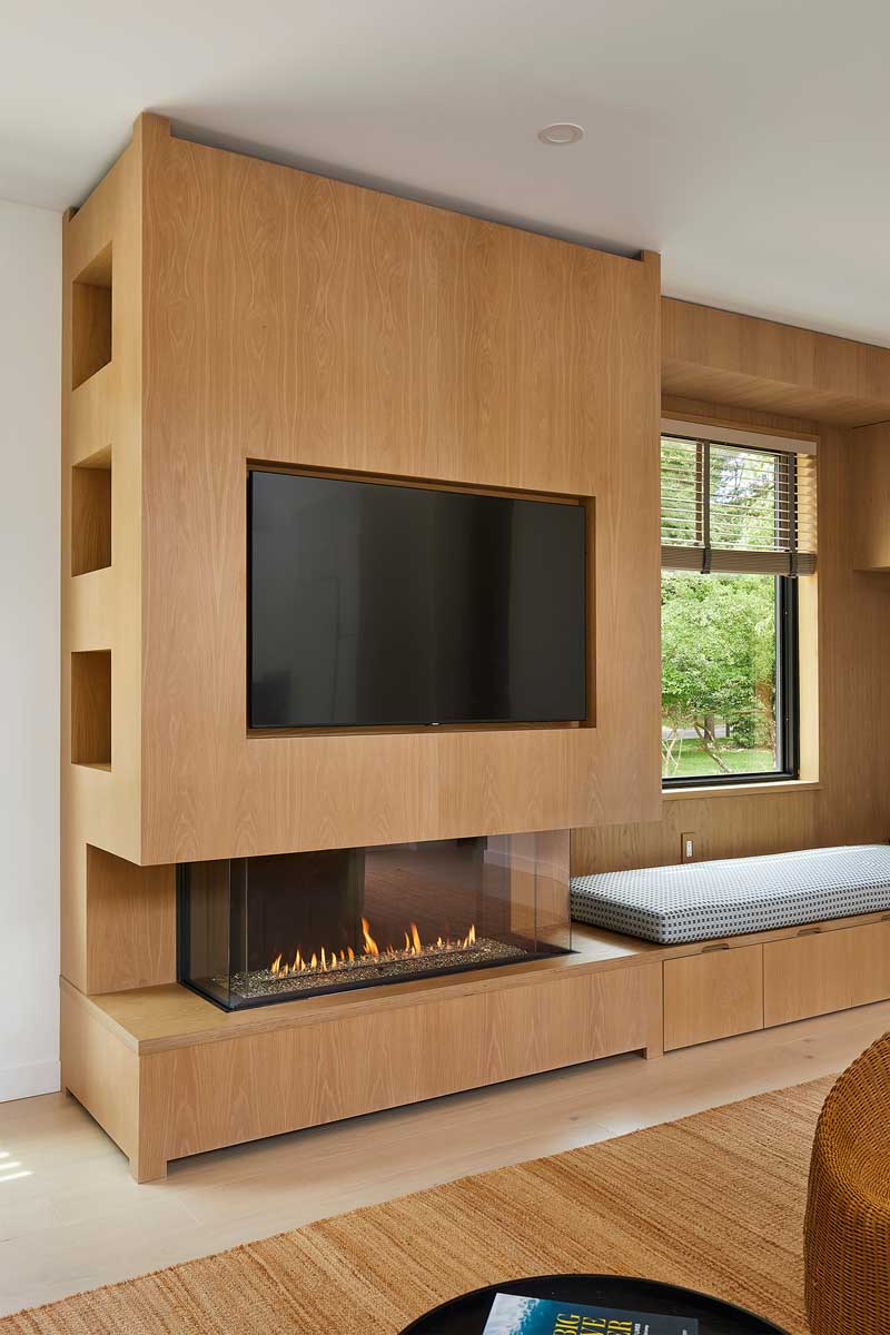 Vestavěná obývací stěna s krbem a televizí kombinuje dřevo s moderním řešením prostoru.