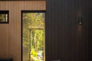 Krytá terasa s křesly a dřevěným obkladem s výhledem do zeleně.