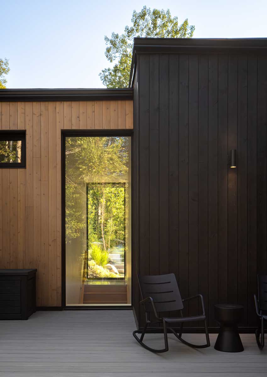 Krytá terasa s křesly a dřevěným obkladem s výhledem do zeleně.