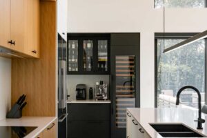 Moderní kuchyň s kombinací dřeva, bílých ploch a vysokým stropem se světlem.