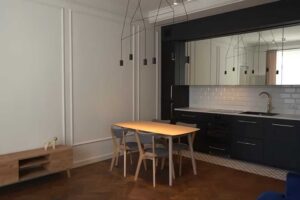 Moderní kuchyně s jídelním stolem a výraznými závěsnými světly v otevřeném obytném prostoru.