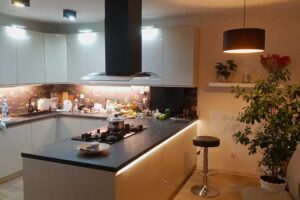 Moderní kuchyně s ostrůvkem a bílými skříňkami v otevřeném obytném prostoru